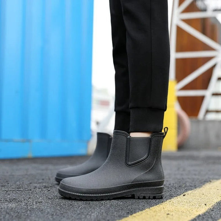 close-up of black rubber Chelsea rain boots worn with cropped pants