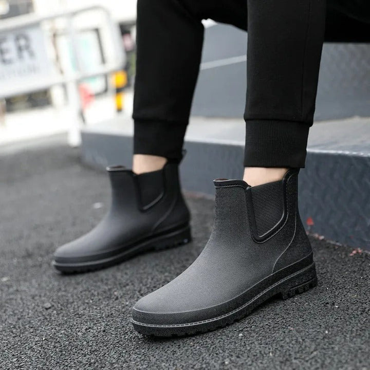 side view of black Chelsea rain boots worn on concrete steps